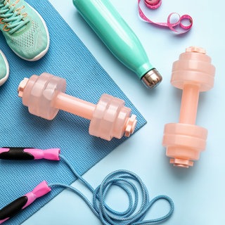 Sportmatte mit Schuhen, Springseil, Flasche und Hanteln