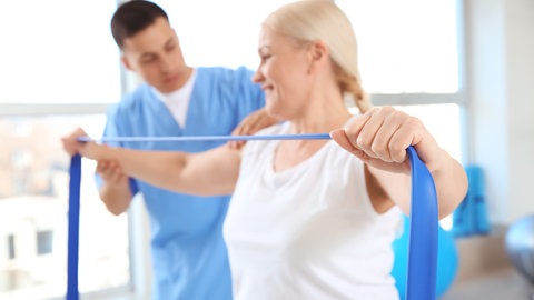 Frau macht Übung mit Theraband