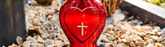 Eine Grabkerze mit Herzsymbol und Kreuz | Eric Wrede: Warum man sich mit seiner Bestattung beschäftigen sollte