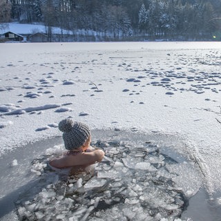 Eine Frau beim Eisbaden im Lauser Weiher bei einer gefrorenen Wasserfläche im Winter. | Schwimmen in extremer Kälte: Wie gesund ist Eisbaden wirklich?