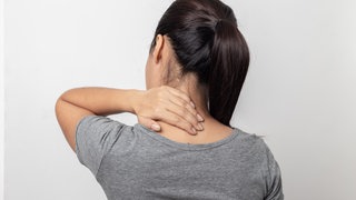 Frau fasst sich in den Nacken