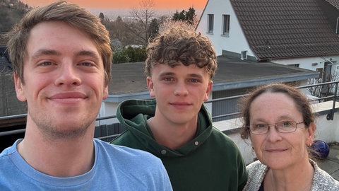 Zwei junge Männer stehen mit ihrer Mutter beim Sonnenuntergang auf einer Terrasse. SWR1 Neuanfang: Nachwuchsfußballer Max und sein Kampf gegen den Krebs. Bei dem jungen Mann aus Heidelberg wird ein Sarkon diagnostiziert, ein höchst aggressiver Krebs. Der Sport und seine Familie geben ihm die Kraft, die Chemotherapie und den Kampf gegen den Krebs erfolgreich zu bestehen.