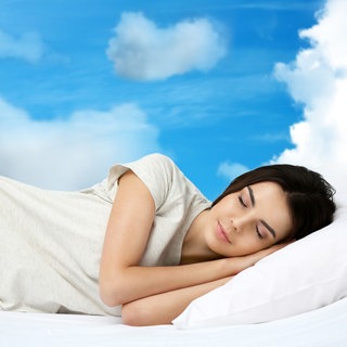 Frau schläft im Bett, Wolken um sie herum 
