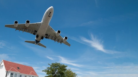 Flugzeug fliegt tief über Haus