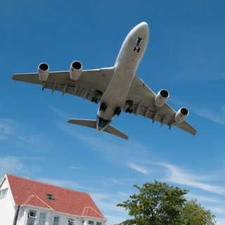 Flugzeug fliegt tief über Haus