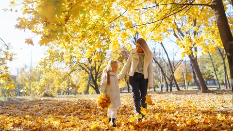 Mutter und Tochter gehen im Herbst im Wald spazieren