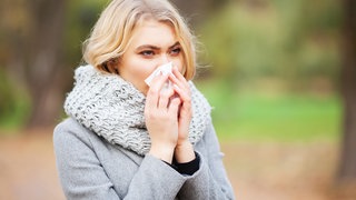 Frau putzt sich die Nase