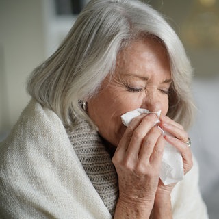 Frau putzt sich die Nase