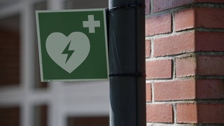 Schild für Defibrillator. KI in Smartwatch erkennt Herzkrankheit