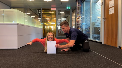 Moderatorin Laura Zacharis und Athletiktrainer Silvester Neidhardt zeigen Übungen, um die Beweglichkeit des eigenen Körpers zu testen.