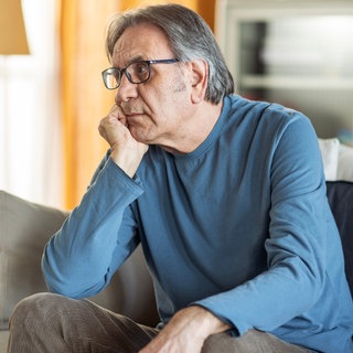 Mann sitzt traurig auf Sofa