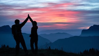 Umgang mit Niederlagen: Menschen die gewandert sind geben sich ein High-Five.