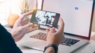 Mann am Smartphone und Laptop