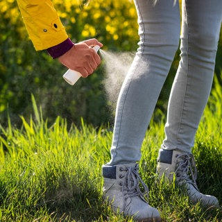 Frau sprüht ihre Hose mit Insektenschutz ein