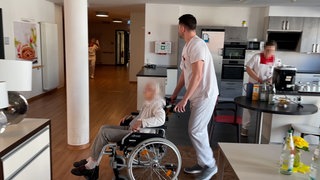 Die Bewohnerin eines Pflegeheims wird im Rollstuhl geschoben.  Die SWR Doku "Mangelware Pflegeplatz" zeigt eine teils absurde Situation in Pflegeheimen.