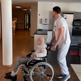 Die Bewohnerin eines Pflegeheims wird im Rollstuhl geschoben.  Die SWR Doku "Mangelware Pflegeplatz" zeigt eine teils absurde Situation in Pflegeheimen.