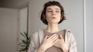 Eine Frau atmet durch. Die tiefe Atmung macht das Seufzen gesund und gibt ihm eine Bedeutung für uns.