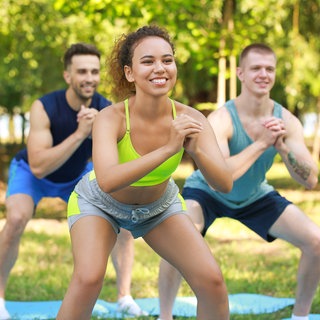 Eine Gruppe junger, sportlicher Menschen, die gemeinsam im Freien trainieren 