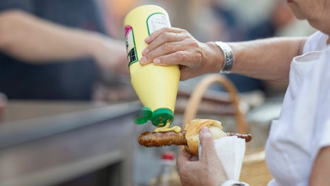 Senf auf Bratwurst. Senf soll gegen Muskelkrämpfe helfen. Doch wissenschaftlich ist der Gesundheitstipp nicht belegt.