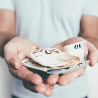 Mann hält Geldscheine in den Händen