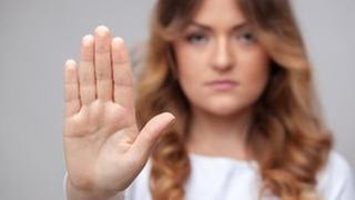 Eine Frau schaut in die Kamera und hält ihre Hand hoch.