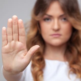 Eine Frau schaut in die Kamera und hält ihre Hand hoch.