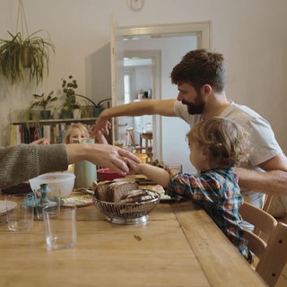 Eine Familie gibt sich vor dem Essen die Hände
