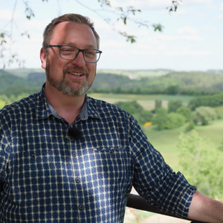 Markus Göbel steht vor einem Ausblick auf die Vulkaneifel.