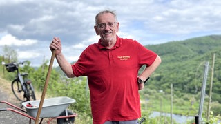 Mann mit Schaufel in der Hand und Moseltal im Hintergrund