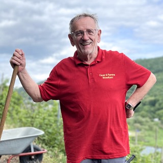 Mann mit Schaufel in der Hand und Moseltal im Hintergrund