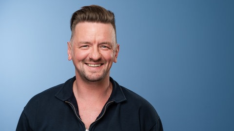 Der Sänger Ben Zucker lächelt in die Kamera.