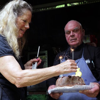 eremit Jakobus Kaffanke feiert seinen 75 Geburtstag. Er trägt einen Geburtstagskuchen.