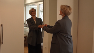 Frau öffnet ihren Kleiderschrank.