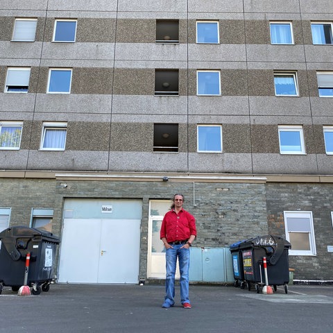 Neuanfang für Alexander nach einem Suizidversuch – hier steht er auf dem Parkplatz vor dem Hochhaus, von dem er sich 1995 in einer schweren Depresion stürzte. Seinen Suizidversuch überlebte er nur durch einen Zufall schwerstverletzt. Dass er den Versuch seiner Selbsttötung überlebt hat, verdankt er einem außergewöhnlichen Zufall. Er will das Thema Suizid aus dem Tabu holen. Er sagt: "Suizidale Menschen möchten nicht sterben, sondern eigentlich nur anders leben". Deshalb hilft er Menschen in tiefen Lebenskrisen.