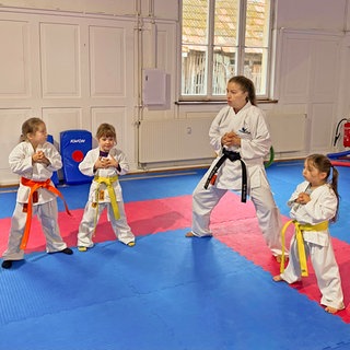 SWR1 Neuanfang: So wurde Mey Alasadi vom Mobbing Opfer zur Karate Meisterin. Mey übt mit Schüler:innen ihrer Karateschule eine Karate-Position. Spielerisch und sportlich lernen die Kinder so Stärke, Selbstbewusstein und Resilienz.