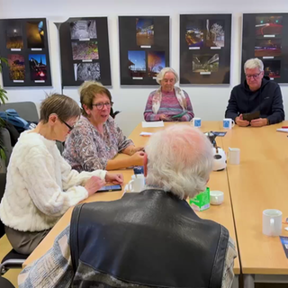 Helga Handke erklärt an einem runden Tisch Senioren das Internet