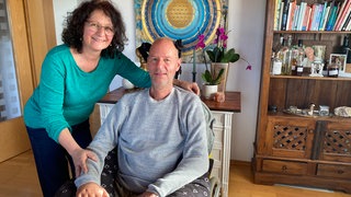 SWR1 Neuanfang: Lebensfreude trotz Krankheit ALS. Stefan und Andrea zu Hause in Engelsbrand am Esstisch. Stefan sitzt im Rollstuhl, er hat die Krankheit ALS, Amyotrophe Lateralsklerose.