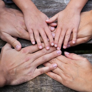 Symbolfoto: Eine Familie hält sich an den Händen. Wieso wird man zu Pflegeeltern? Ein Pflegevater erzählt. 
