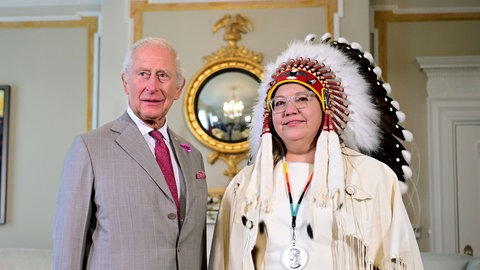 König Charles steht neben einer Frau mit traditionell indigenem Kopfschmuck in Kanada.