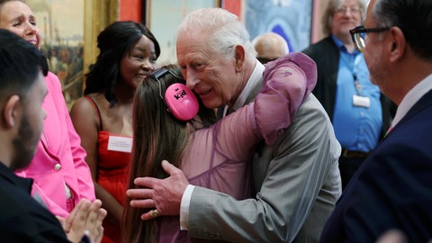 König Charles III. umarmt das Mädchen Florence Mcgrellis während eines Besuchs in der Cartwright Hall, einer Kunstgalerie und Kulturstätte in Bradford.