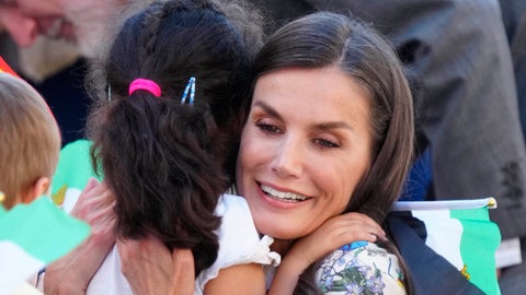 Königin Letizia von Spanien nimmt ein kleines Mädchen lächelnd in den Arm.