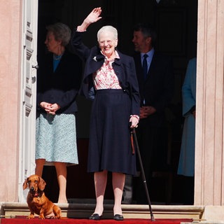 Königin Margrethe steht an ihrem 84. Geburtstag vor Schloss Fredensborg und winkt fröhlich.