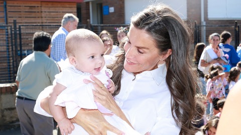 Königin Letizia hält freudestrahlend ein Baby auf dem Arm.
