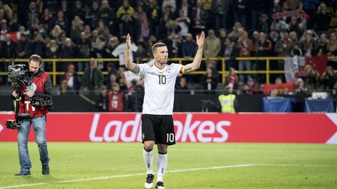 Lukas Podolski steht nach dem Spiel mit ausgebreiteten Armen auf dem Rasen.