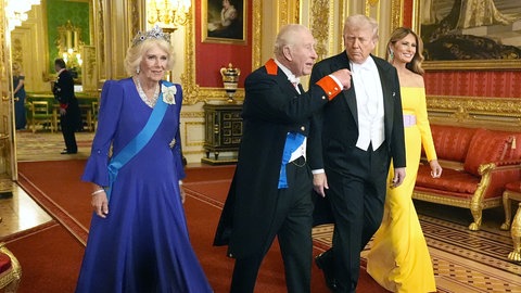 König Charles und US-Präsident Donald Trump laufen nebeneinander in Schloß Windsor in Begleitung von Camilla und Melania. Charles redet mit Trump.