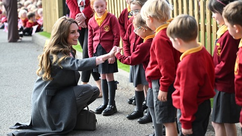 Kate, Prinzessin von Wales, spricht zu Schülern während eines Besuchs in der Farnborough Road Infant and Junior School in Birkdale und hockt sich vor ihnen auf den Boden.