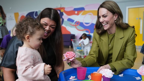 Die Prinzessin von Wales besucht die Organisation Home-Start in Oxford, trägt dabei einen grünen Anzug, schenkt einem Mädchen eine Rose und lacht dabei.