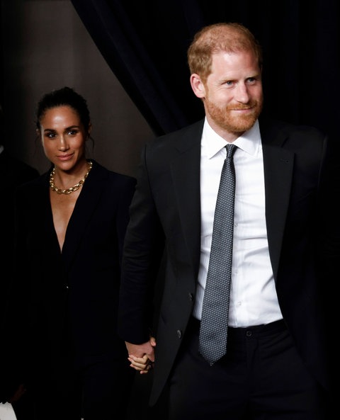 Prinz Harry und Herzogin Meghan gemeinsam hand in Hand auf einer Award-Verleihung in New York. Beide sind in schwarz gekleidet und lächeln.
