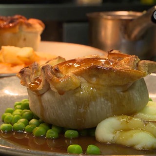 Pie, Kartoffelpüree und Erbsen auf einem Teller angerichtet