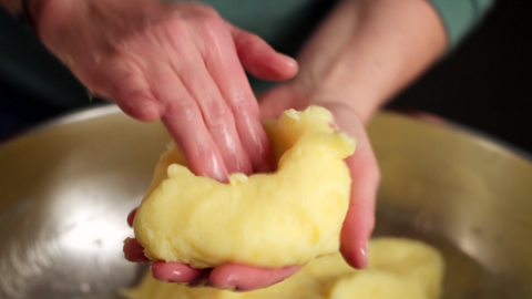 Roher Kloßteig, der mit Händen geformt wird. Thüringer Klöße mit gerösteten Brötchenwürfeln gefüllt - zubereitet aus Kartoffeln, Salz, etwas Butter, Brötchen und ohne weitere Zusatzstoffe.